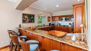 A spacious kitchen with a curved island, wooden cabinets, and a large window providing natural light. - Mariners Point C1 – 3-Bedroom Villa on Bluff Above Playa Hermosa with Private Pool (Playa Hermosa)