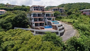 A large, multi-story house with a swimming pool and multiple balconies, surrounded by lush greenery. - Mariners Point C1 – 3-Bedroom Villa on Bluff Above Playa Hermosa with Private Pool (Playa Hermosa)