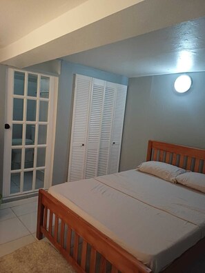 A bedroom with a bed, a wardrobe, and a door. - Village Comfort  (Belmont)