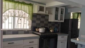 A kitchen with a stove, oven, cabinets, and a refrigerator. - Village Comfort  (Belmont)