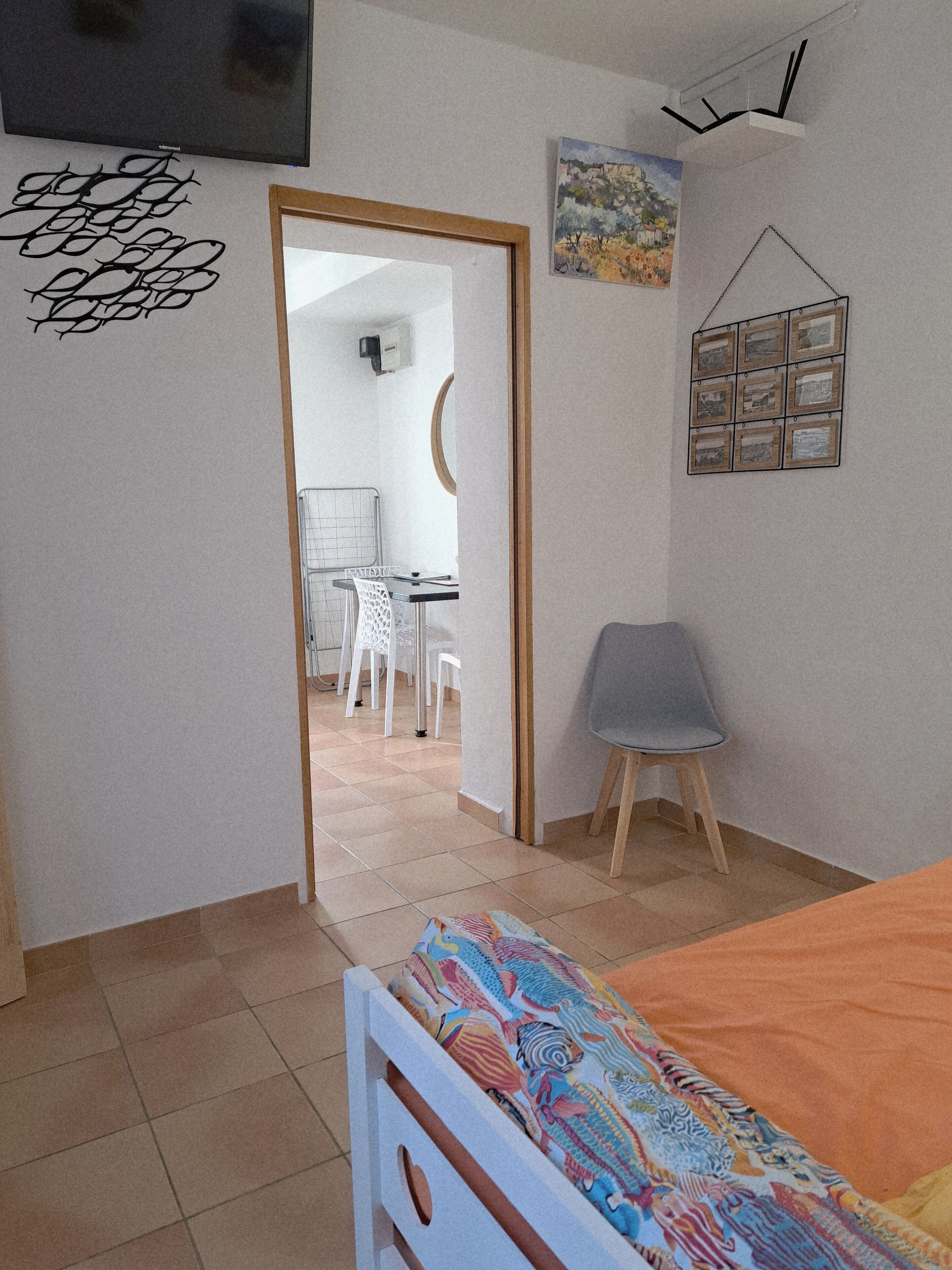 A bedroom with a bed, a desk, and a chair. There is a door leading to another room.
