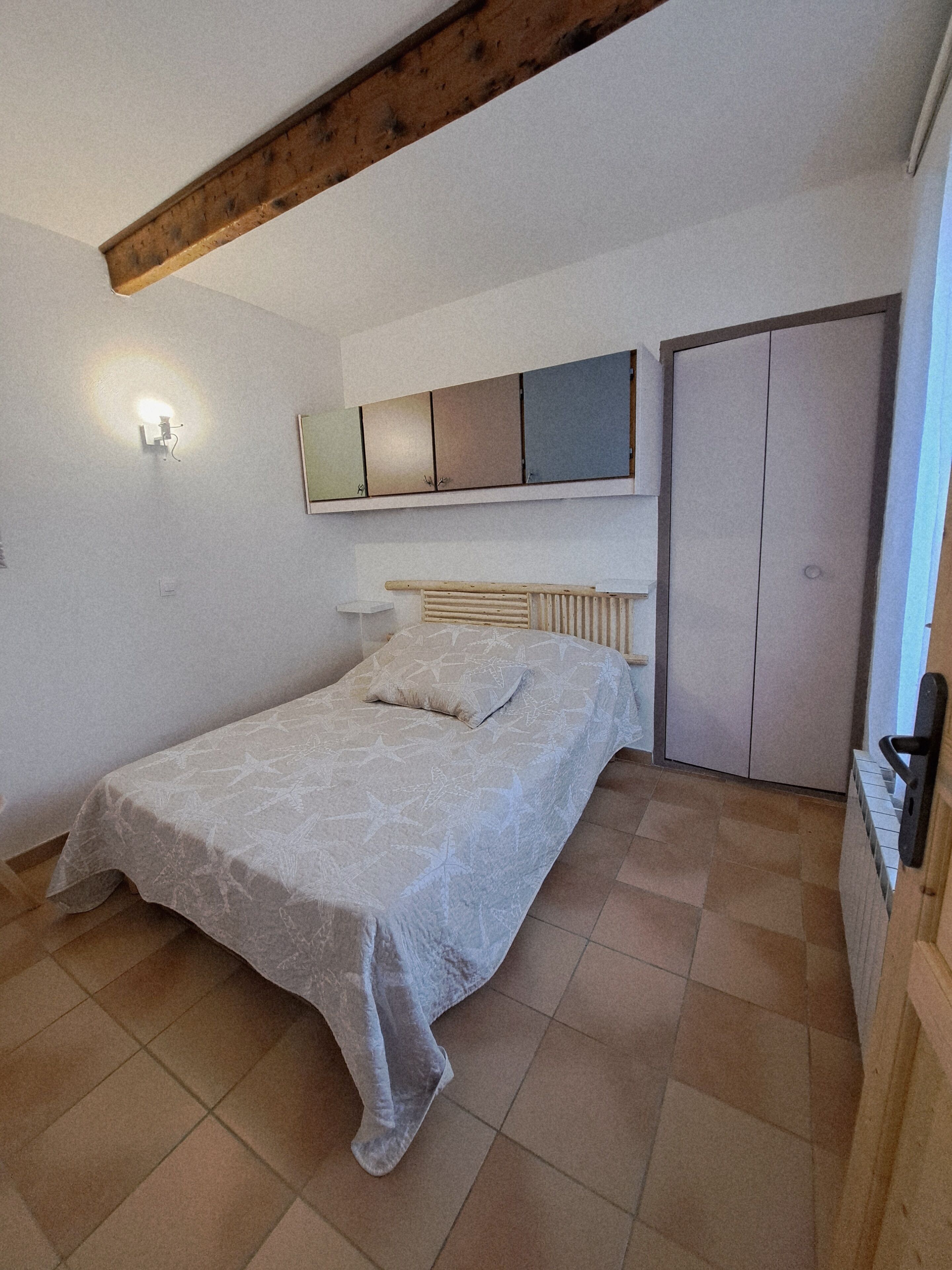 Une chambre à coucher avec un lit, une armoire et un miroir au mur.