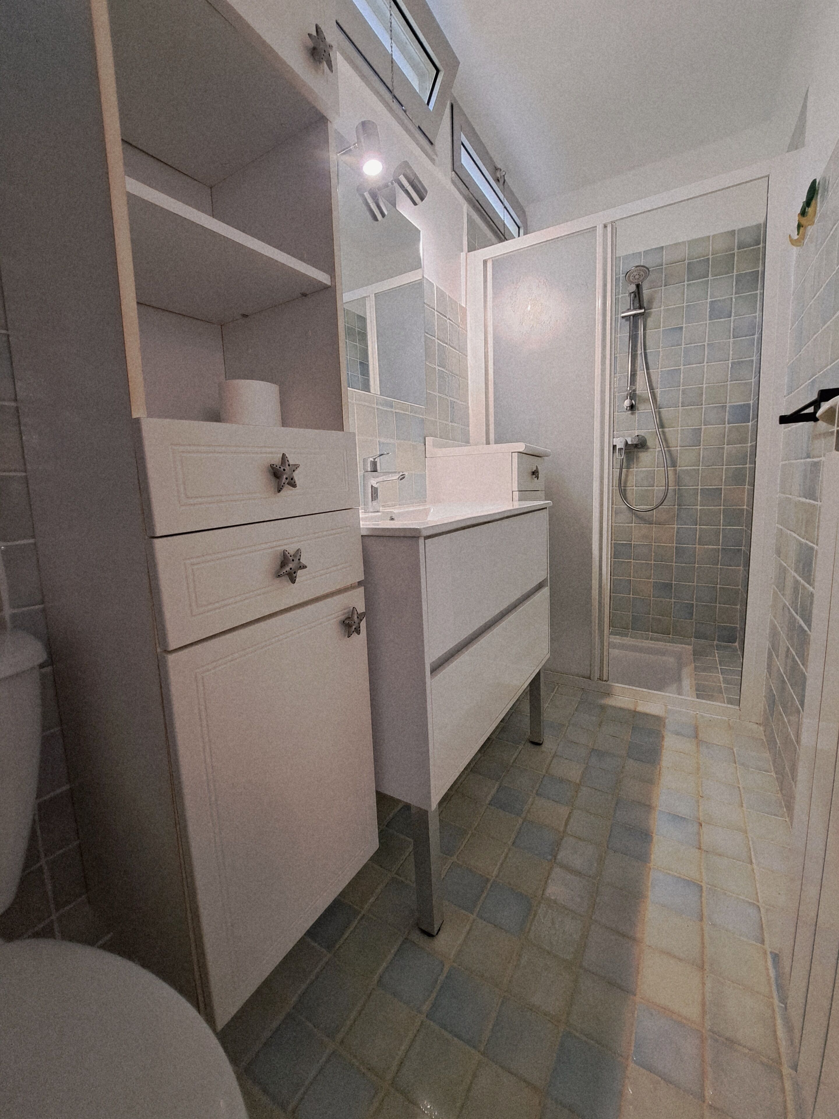 Un baño con tocador blanco, ducha e inodoro.