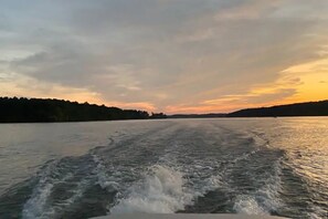 Vene lipuu vesistön poikki, ja taustalla näkyy auringonlasku.