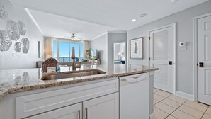 A modern kitchen with white cabinetry, a granite countertop, and a built-in dishwasher.