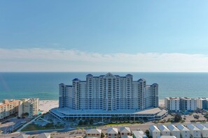 Un hôtel de grande hauteur, avec de nombreux étages, une vue sur la plage et un parking.