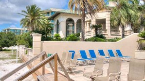Un resort con piscina, sillones de descanso y un edificio grande con ventanas arqueadas y palmeras.