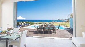Un comedor con vistas al mar, una piscina y mobiliario de exterior.