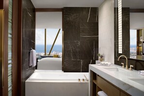A modern bathroom with a bathtub, a large mirror, and a view of the city.