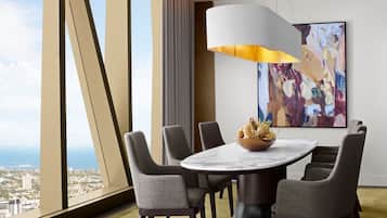 A modern dining area with a round table, six grey upholstered chairs, a marble top, and a large abstract painting on the wall.