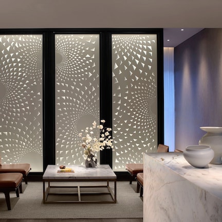 A modern lobby with a reception desk, seating area, and decorative panels.
