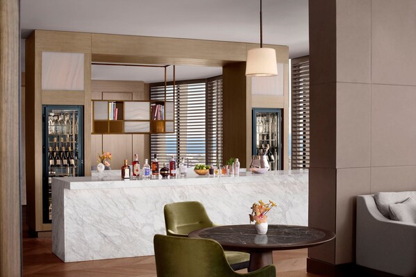A modern kitchen with a marble island, green chairs, and a round table with a vase of flowers. - The Ritz-Carlton, Melbourne (Melbourne)