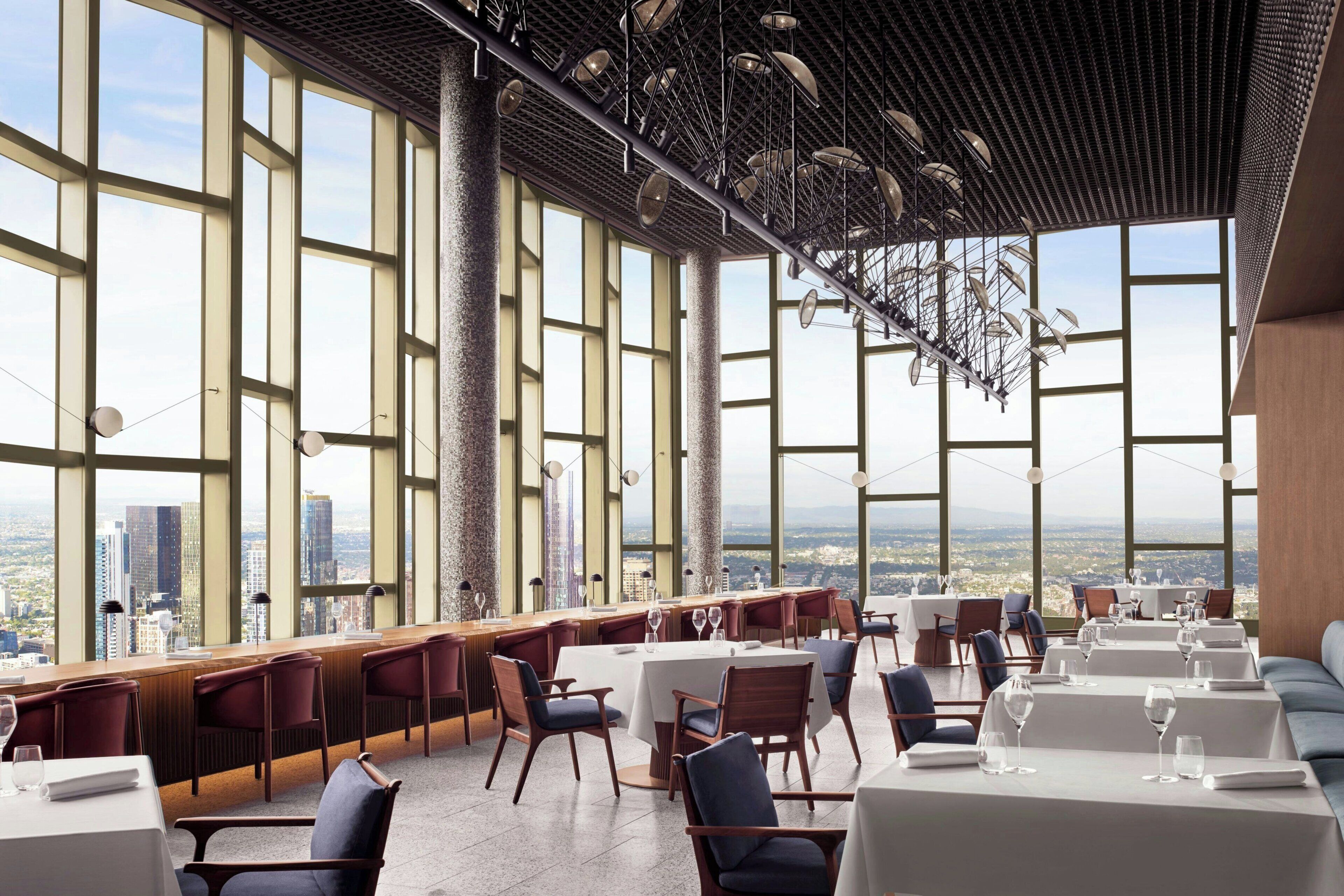 A high-rise restaurant with large windows offering city views, modern interior design, and a variety of seating arrangements.