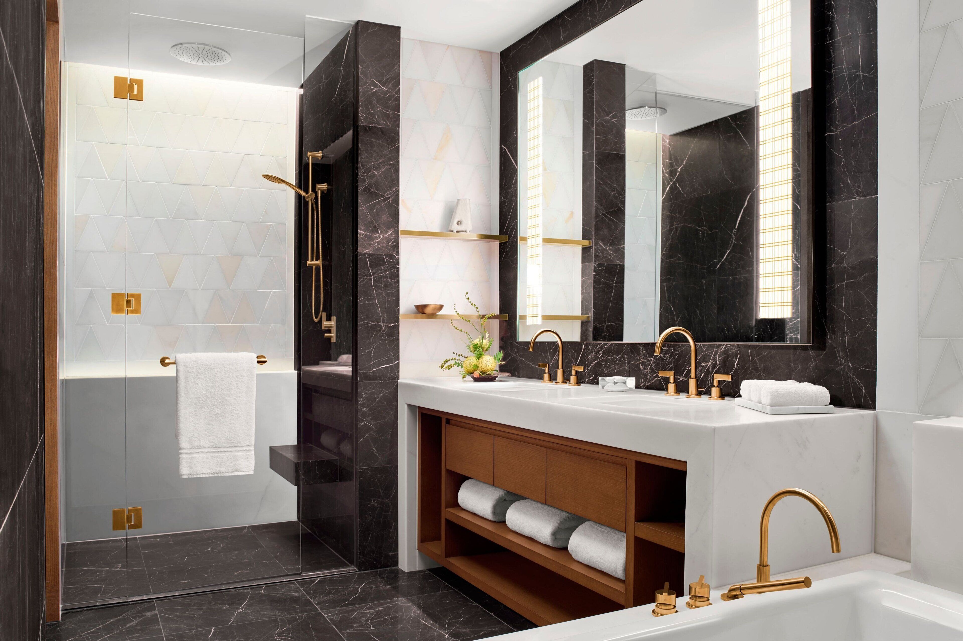 A modern bathroom with a large mirror, dual sinks, and a walk-in shower.
