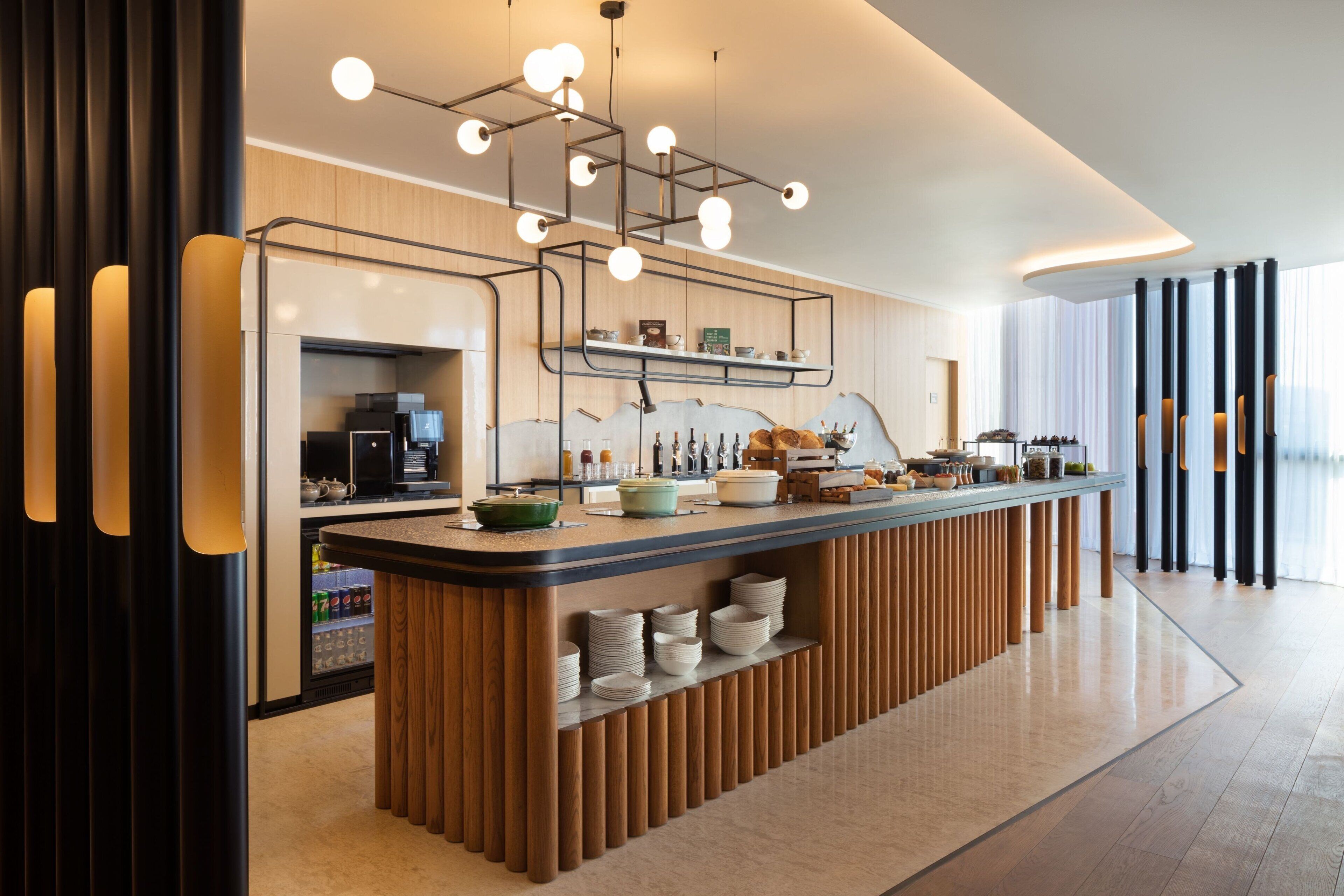 Una cocina moderna con una isla central, electrodomésticos integrados y una lámpara colgante.