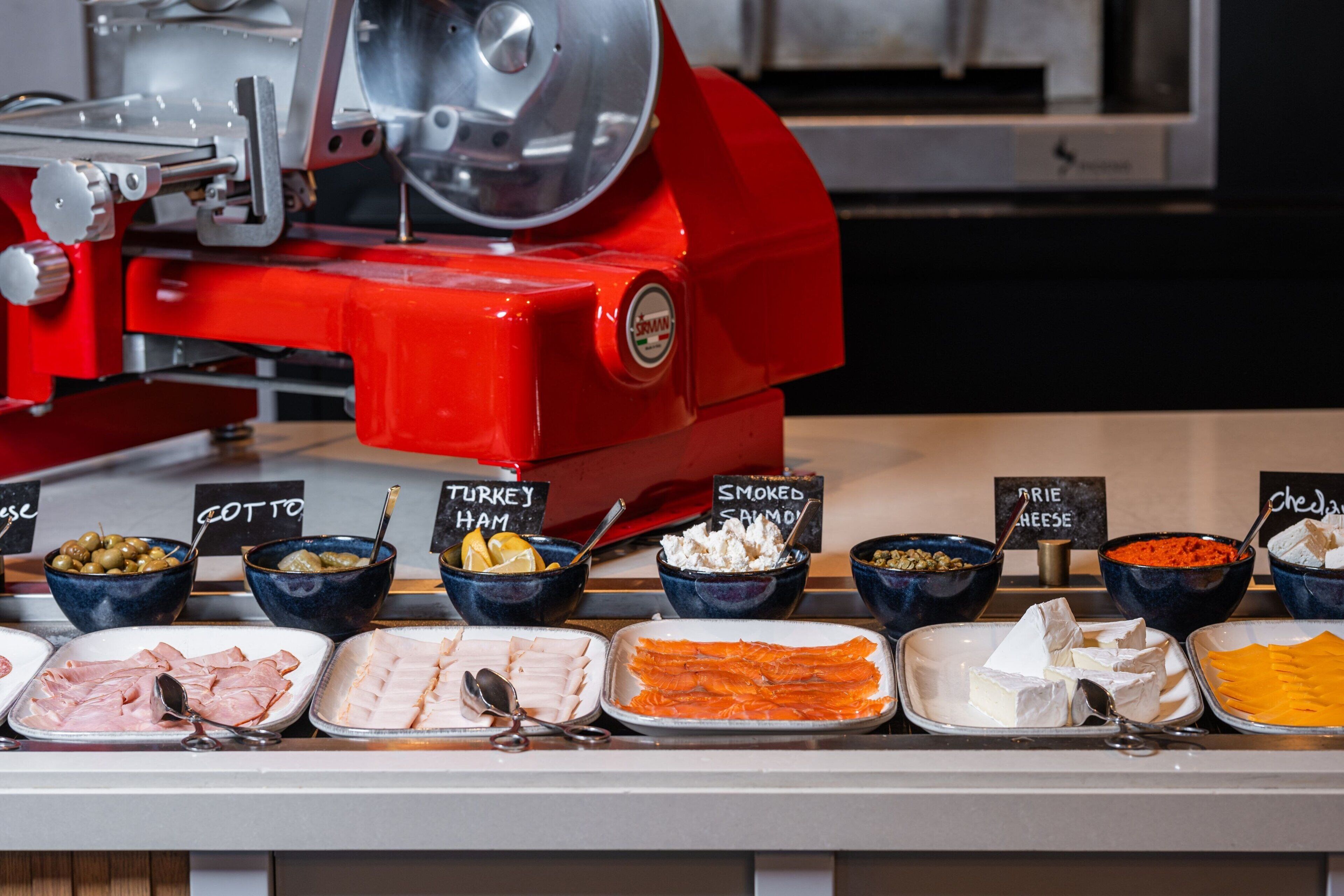 Un buffet proposant une variété de plats, notamment du jambon, de la dinde, du saumon fumé et du fromage.