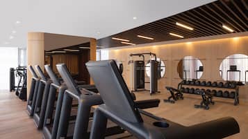 A modern gym with treadmills, weight machines, and a mirror wall.