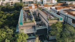 Een modern meerlaags gebouw met dakterrassen, buiten zitplaatsen en beplanting.