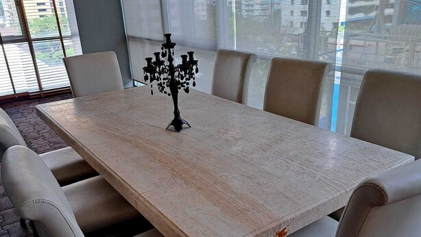 A rectangular dining table with a dark, ornate centerpiece, surrounded by six beige upholstered chairs. - 2D - 3 Bedroom Downtown Apartment With Shared Pool (Bangkok)