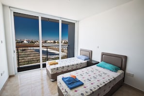 A bedroom with two beds, a balcony with a view, and a sliding door. - Protaras Pearl Villa Pe16 (Paralimni)