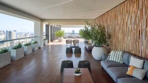 A spacious balcony with a city view, modern furniture, and potted plants. - Luxury Condo 1 Br Pool Excellent Location (Santo Domingo)