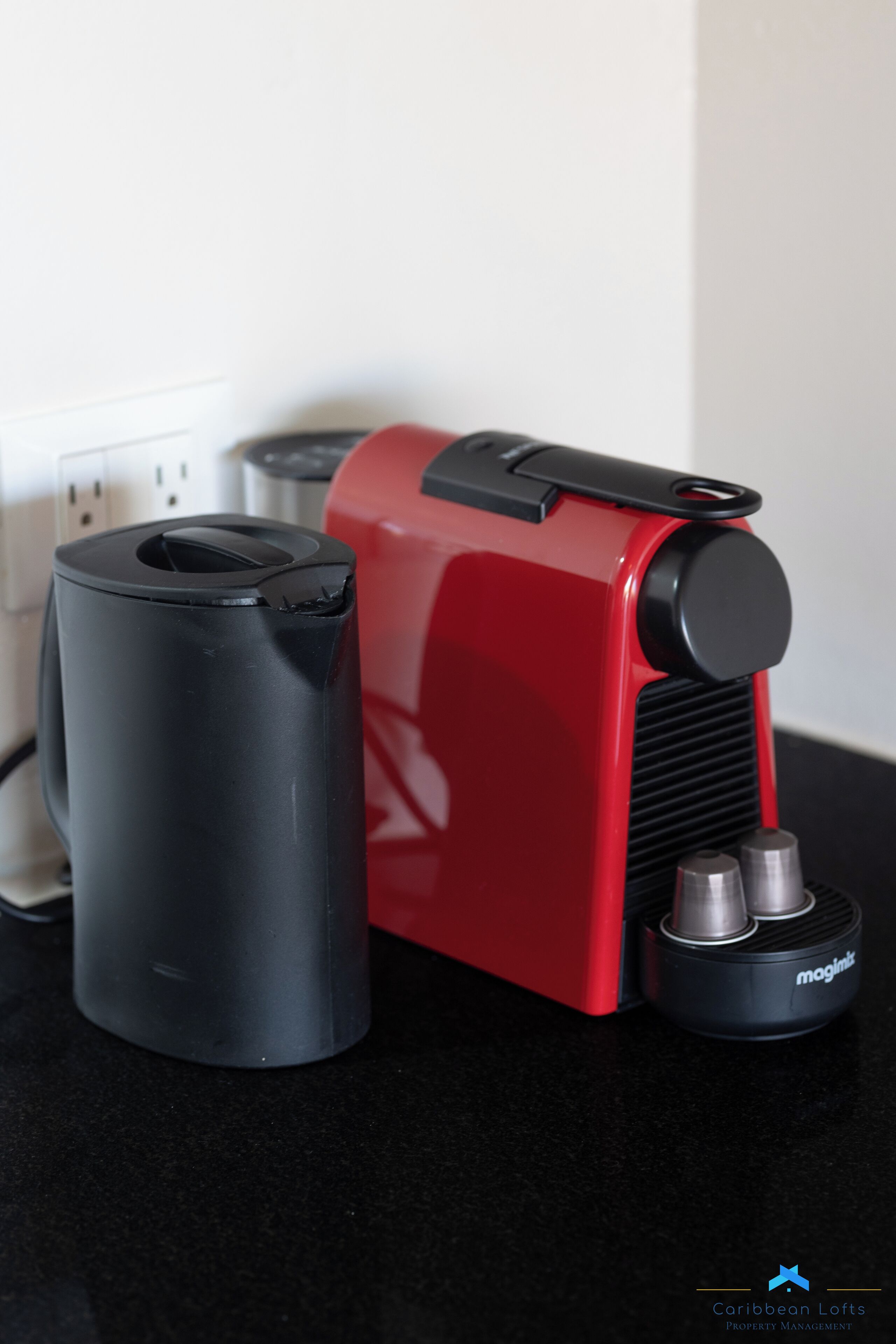 Een rode en zwarte koffiemachine op een zwart aanrecht.