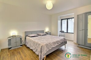 Une chambre à coucher avec un lit, des tables de chevet, une armoire et une fenêtre.