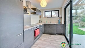 Una cucina moderna con mobili grigi, forno a incasso, lavello e finestra con vista su un giardino.