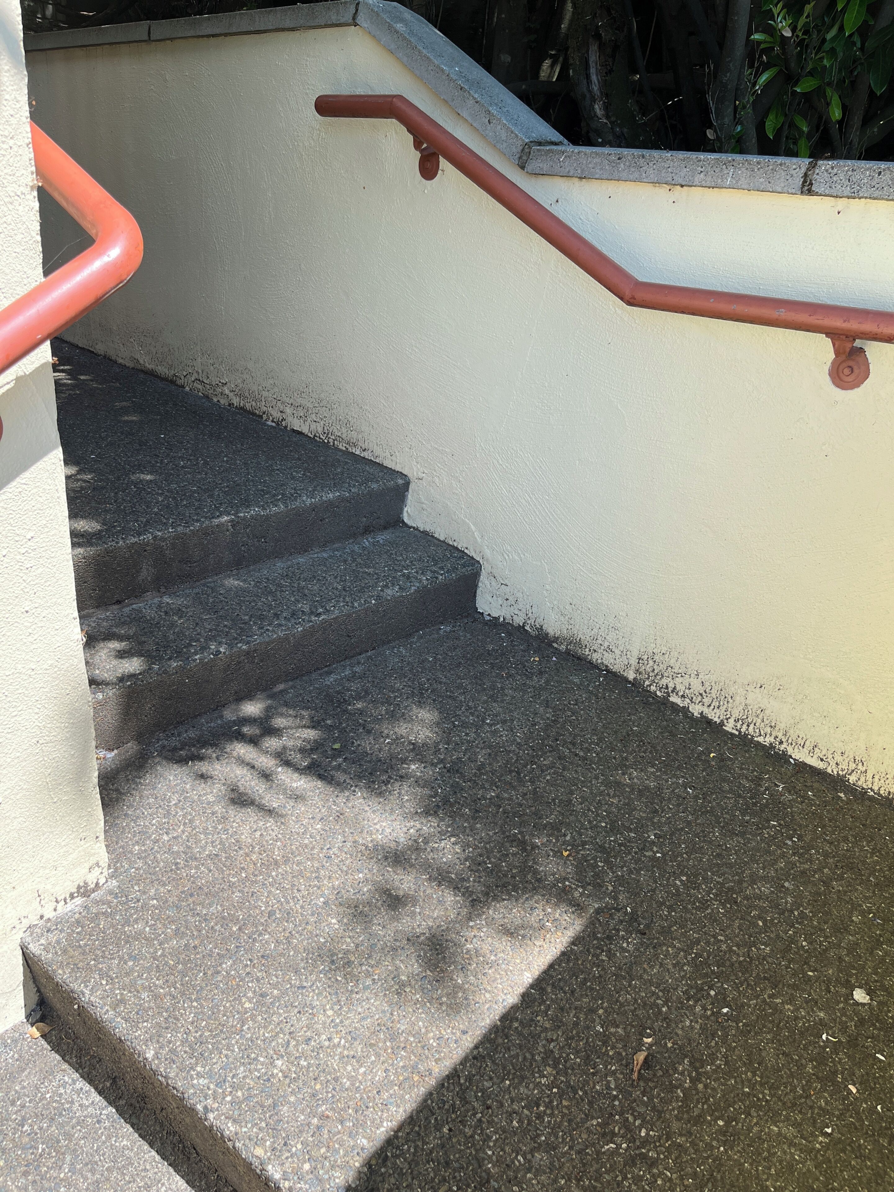 A set of concrete steps with a metal handrail, leading to a higher level.