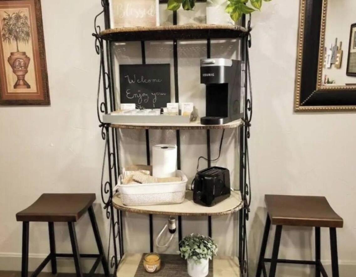 Een koffiehoek met een koffiezetapparaat, een prikbord en een kleine plant.