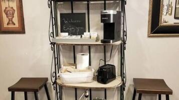Een koffiehoek met een koffiezetapparaat, een prikbord en een kleine plant.