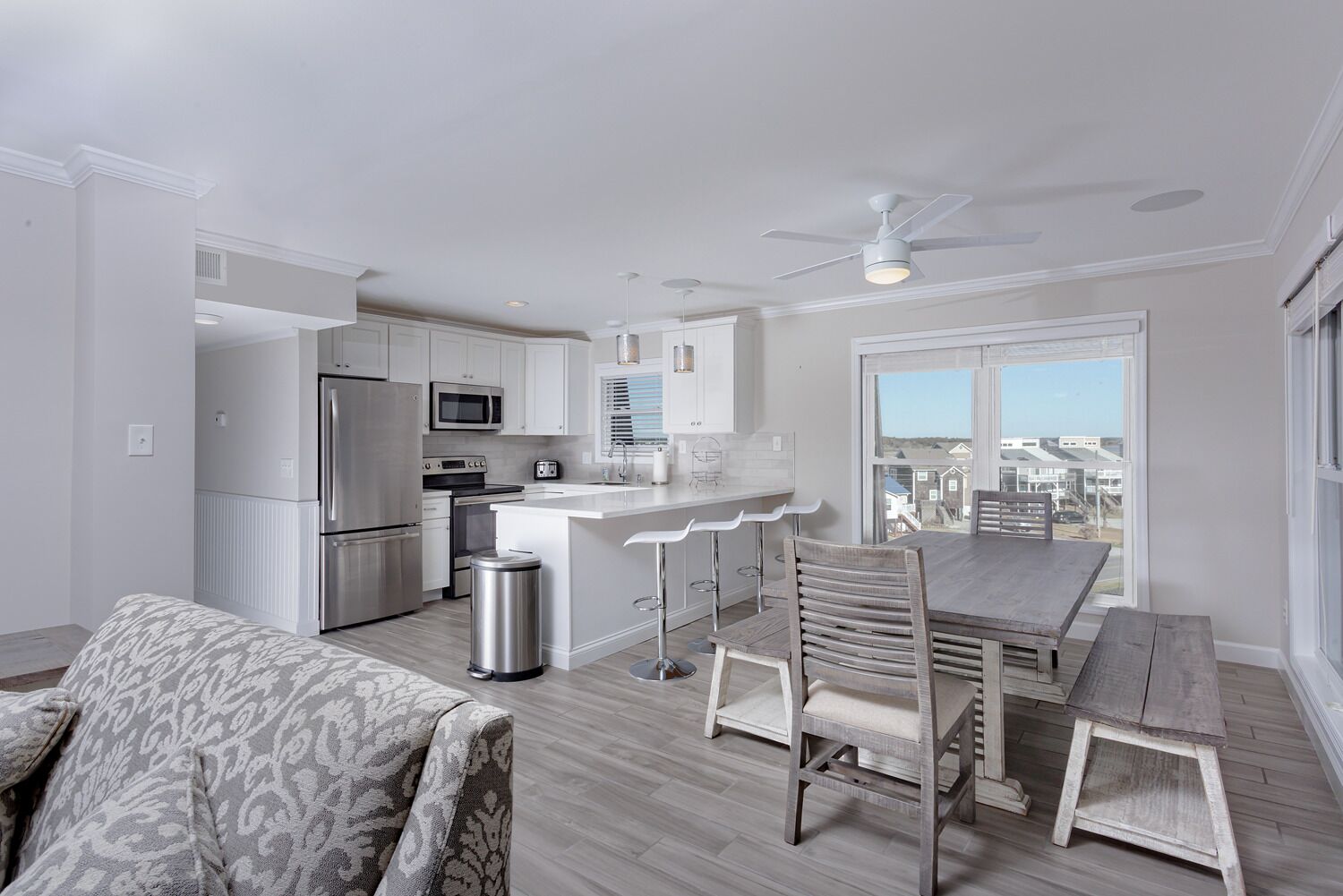 A modern kitchen with white cabinets, stainless steel appliances, and a bar area.