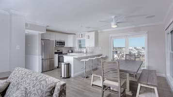 A modern kitchen with white cabinets, stainless steel appliances, and a bar area.