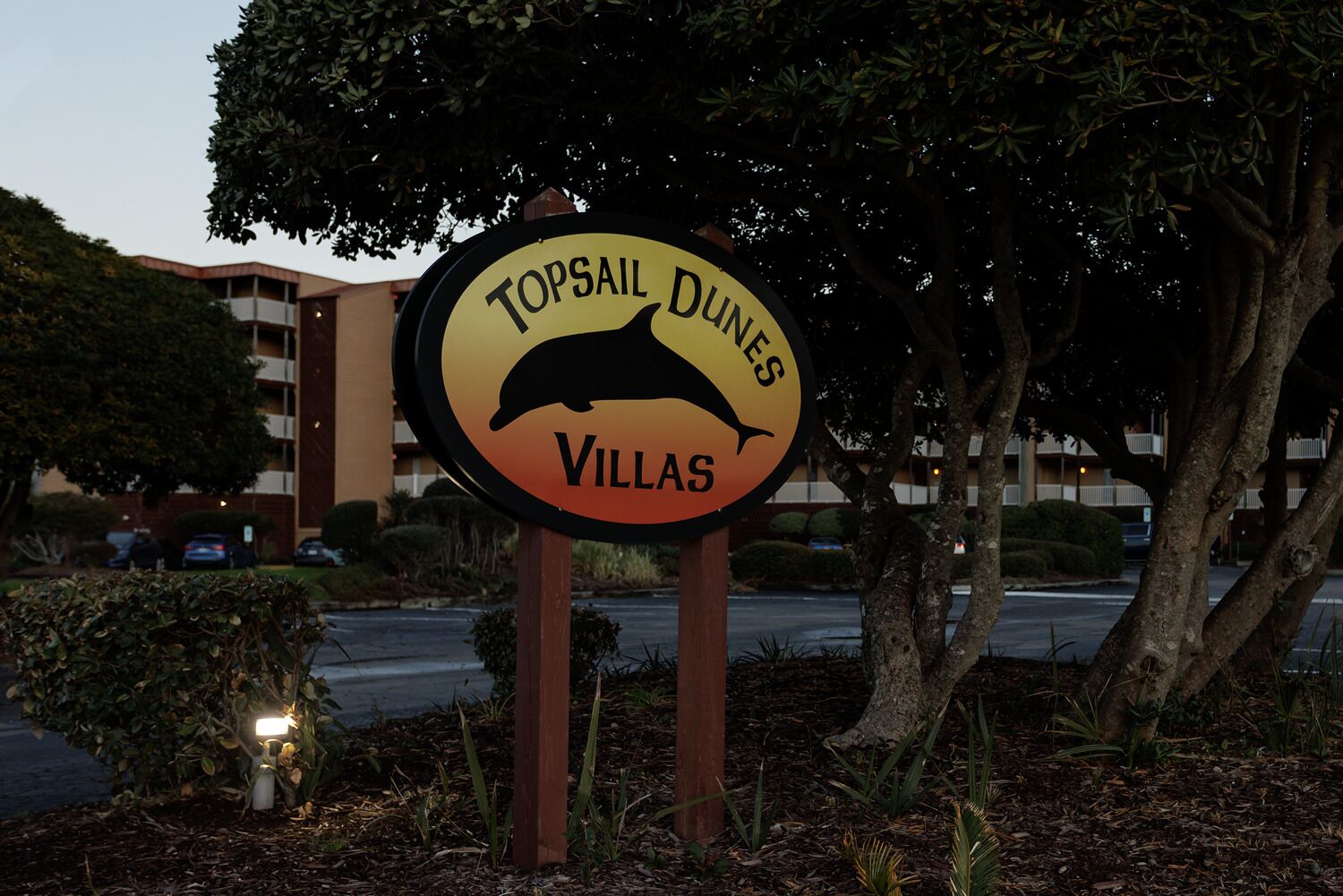 A sign for Topsail Dunes Villas with a dolphin graphic.