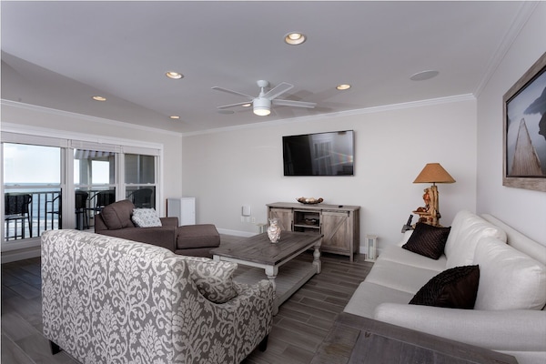 Open living area just off the kitchen/dining area with couch, chaise, and settee