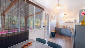 Eine moderne Küche mit integriertem Geschirrspüler, Spüle und Kühlschrank. Ein Essbereich mit Tisch und Stühlen ist ebenfalls vorhanden.