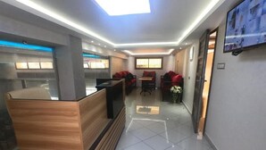 A hotel lobby with a reception desk, seating area, and a TV mounted on the wall. - Appartment with Moroccan breakfast (Dakhla)