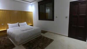 A bedroom with a bed, wooden headboard, a window, and a door. - Appartment with Moroccan breakfast (Dakhla)