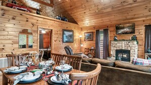 Ein gemütliches Blockhaus-Interieur mit Essbereich, Kamin und Holzwänden.
