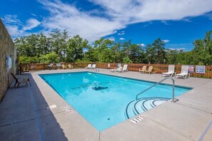Une piscine rectangulaire avec une terrasse en bois et des chaises longues.