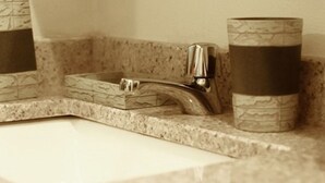 A bathroom with a granite countertop, a sink with a chrome faucet, and two marble-patterned containers. - 5 minutes from eagle beach as an apartment with kitchen and (Noord)