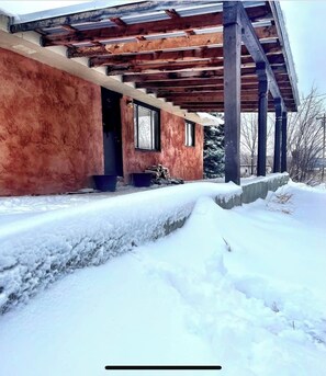 Set amidst a serene winter landscape, this building features a covered porch with a pergola structure.