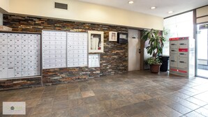 A reception area with a stone wall, mailboxes, a potted plant, and a door to the right.