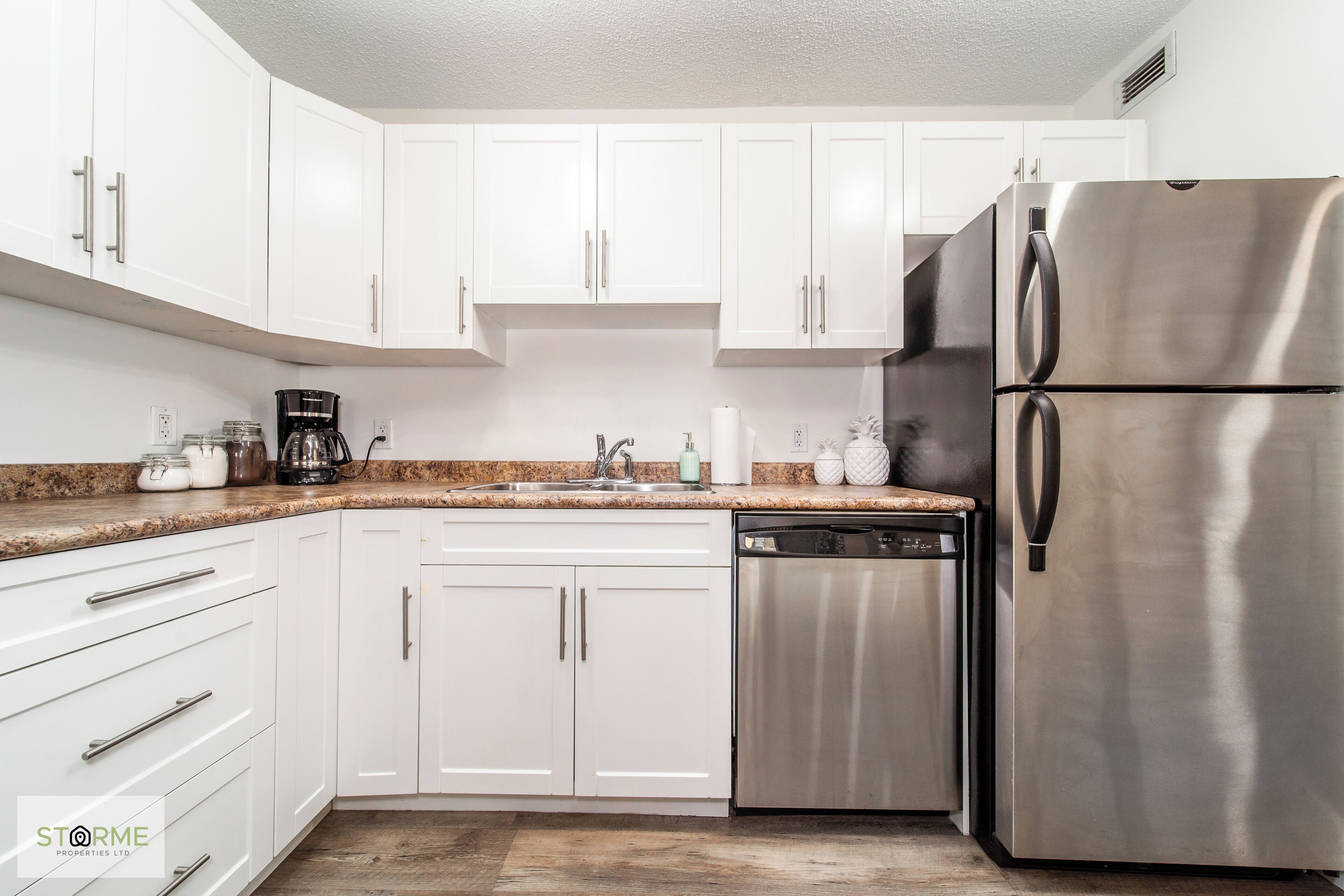 A modern kitchen with white cabinets, stainless steel appliances, and a granite countertop.