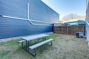 Patio trasero con mesa de picnic y unidad de aire acondicionado.
