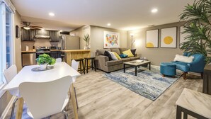A modern living room with a sofa, coffee table, and dining area. There is a kitchen with appliances and a dining table. - Cozy Newport Cottage Near Stadiums & Downtown (Newport)