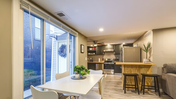 A modern kitchen with a dining area, large windows, and a ceiling fan. - Cozy Newport Cottage Near Stadiums & Downtown (Newport)