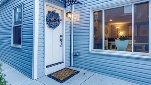 A house with a front door, a doormat, a wreath, and a window with a view into the interior. - Cozy Newport Cottage Near Stadiums & Downtown (Newport)