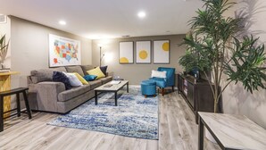 A modern living room with a grey sofa, blue armchair, and a coffee table. - Cozy Newport Cottage Near Stadiums & Downtown (Newport)