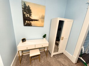 A room with a desk, a bench, a wardrobe, and a painting of a lake.